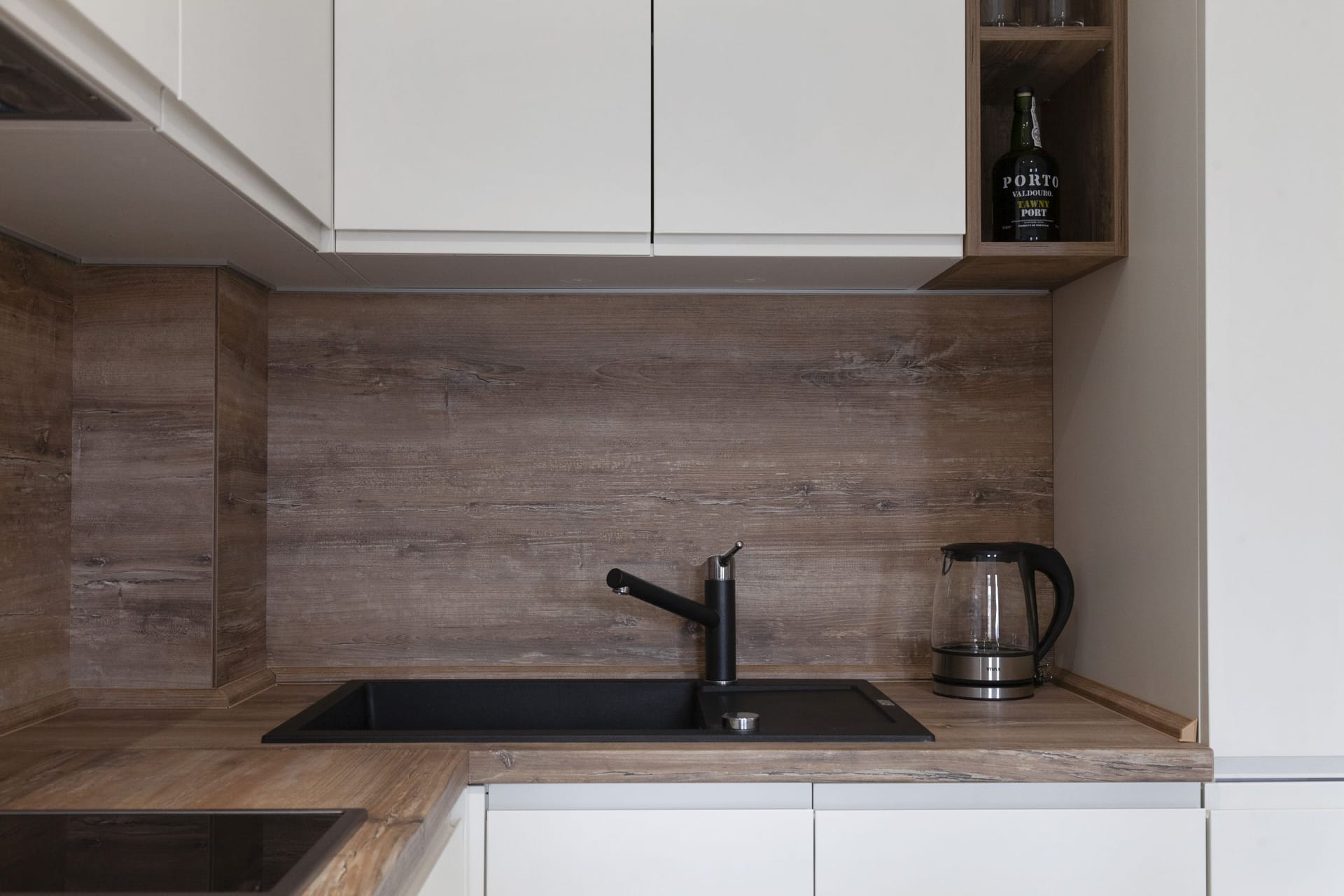Modern kitchen with white fronts and a wooden countertop in an apartment in Kotor, Montenegro: black sink and faucet.