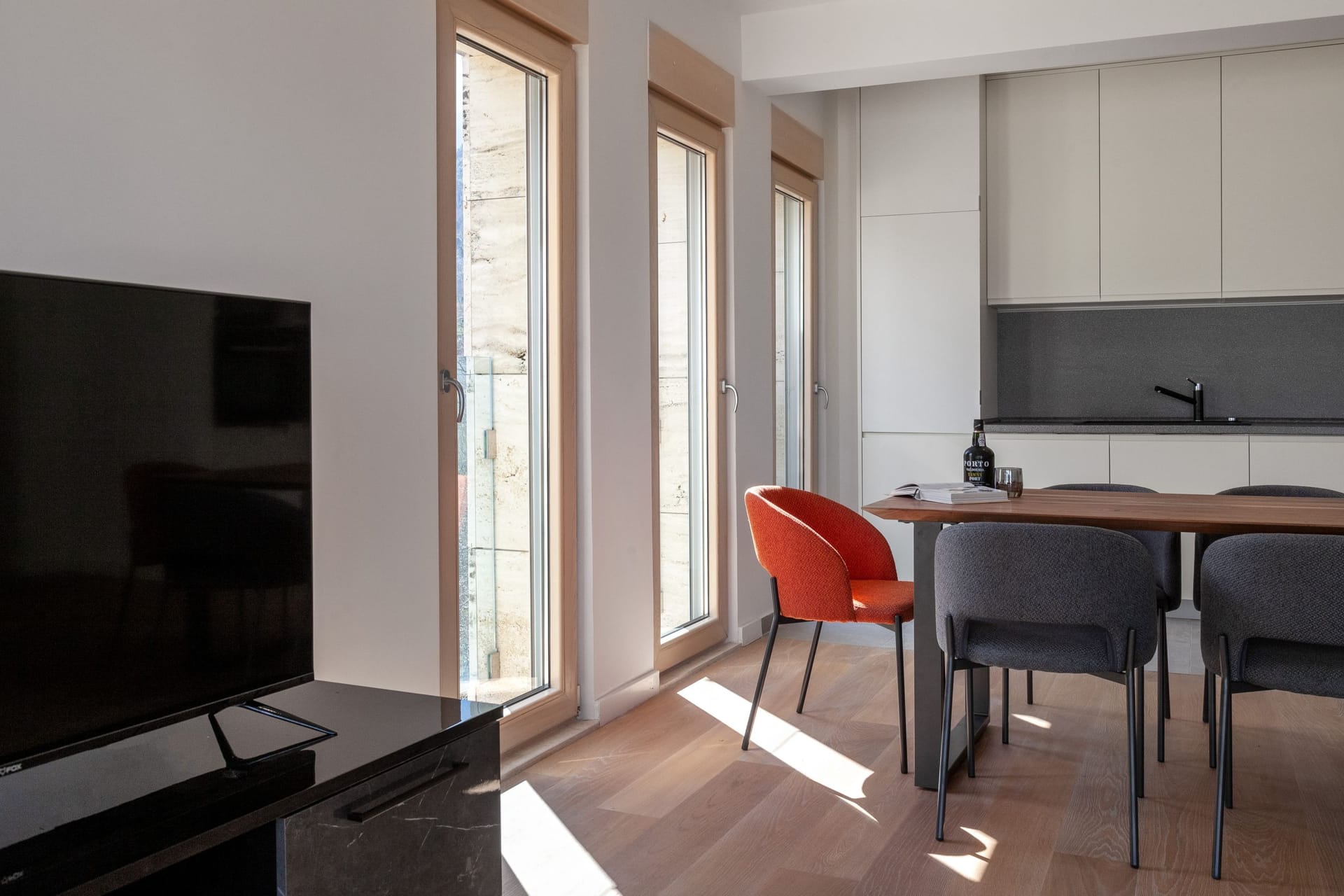 Modern living room with kitchen in an apartment, Kotor, Montenegro: bright interior, wooden floor, and dining area.