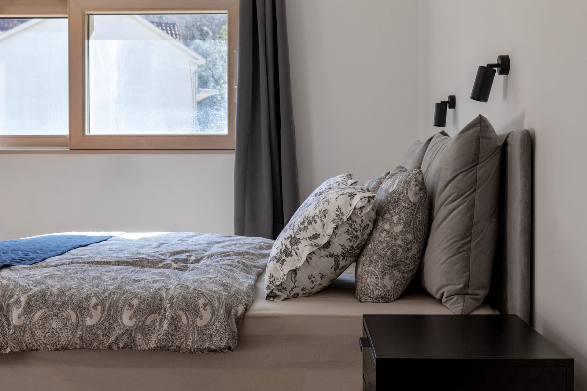 Modern bedroom in an apartment in Kotor, Montenegro: double bed, stylish textiles, and a view from the window.