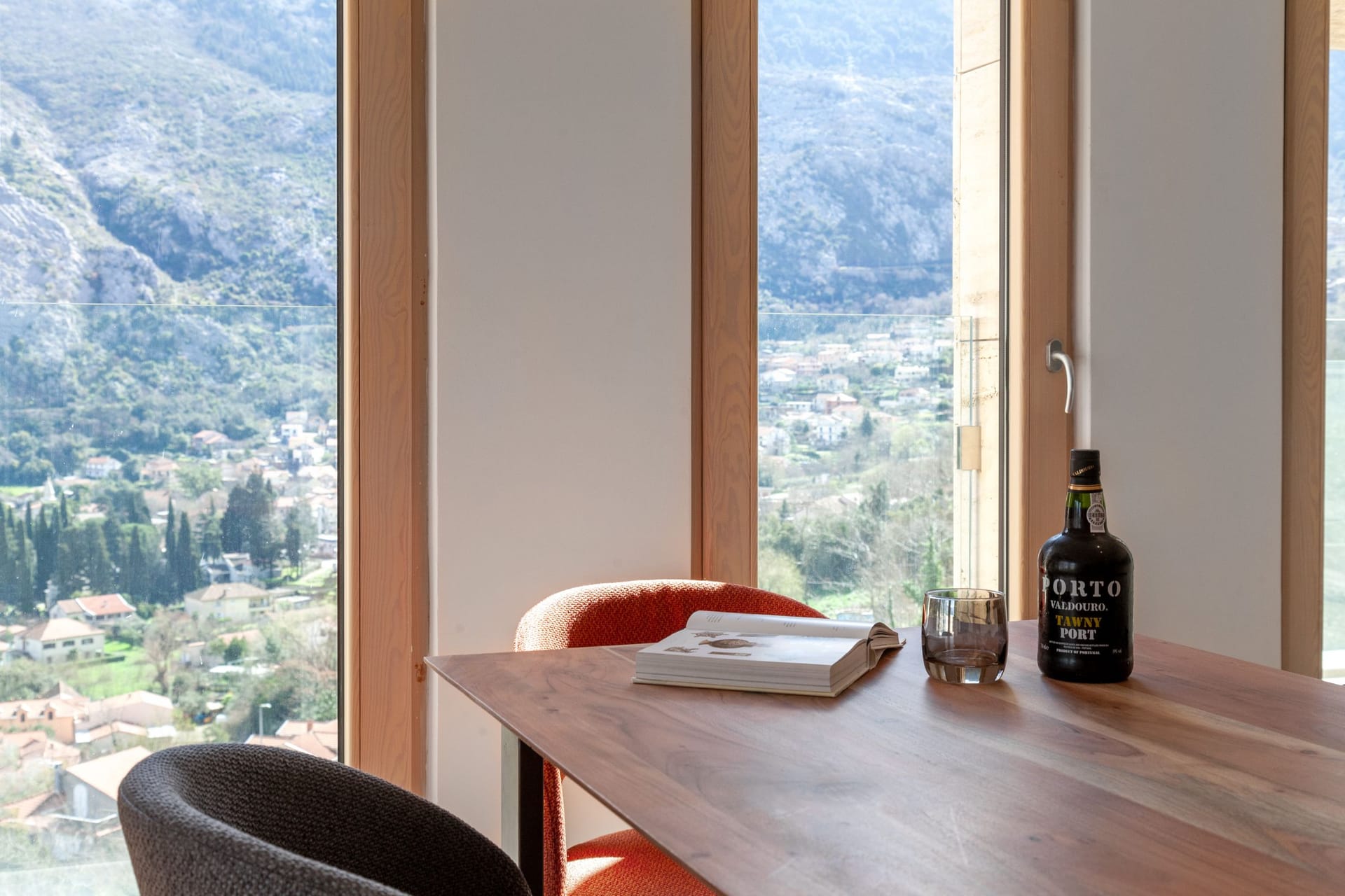 Living room with panoramic views of the mountains and the city of Kotor, Montenegro: a wooden table, stylish armchairs, and a cozy interior.