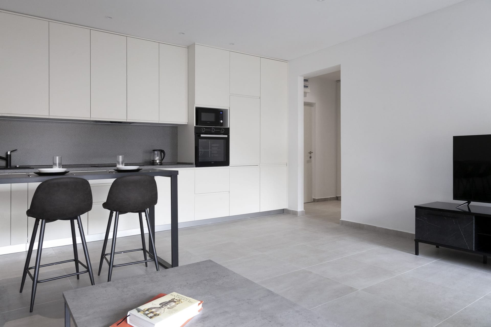 Modern kitchen-living room in an apartment in Kotor, Montenegro: light cabinetry, a breakfast bar, and built-in appliances.