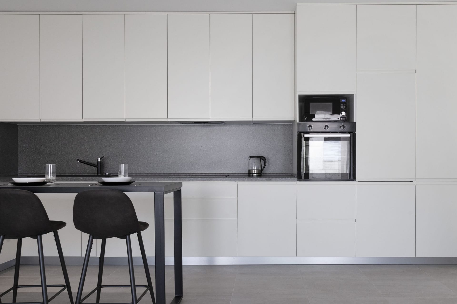 Modern kitchen in an apartment in Kotor, Montenegro: light cabinetry, built-in appliances, and a bar counter with stools.
