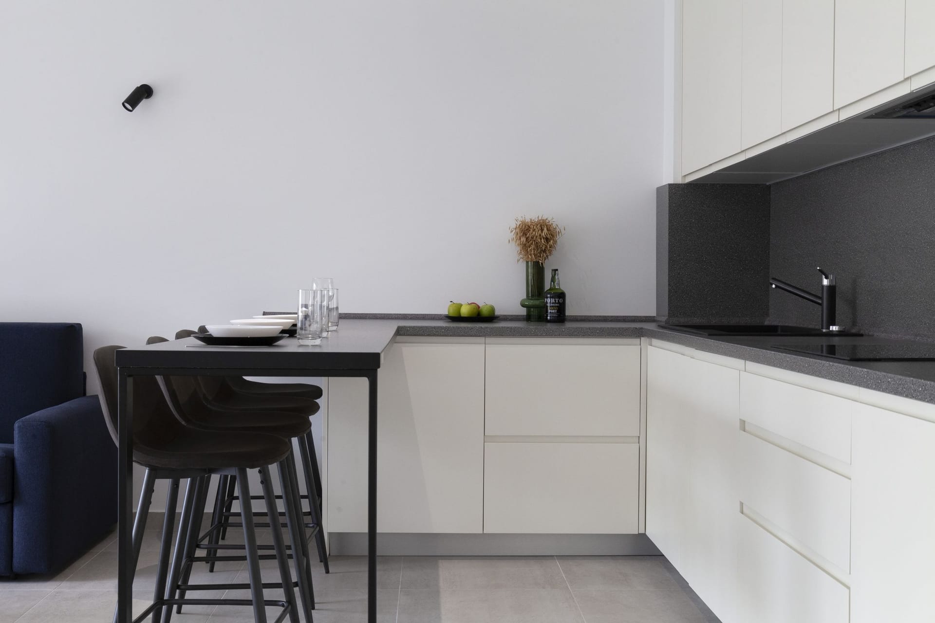 Modern kitchen in an apartment in Kotor, Montenegro: white cabinets, dark countertop, and a breakfast bar with stools.