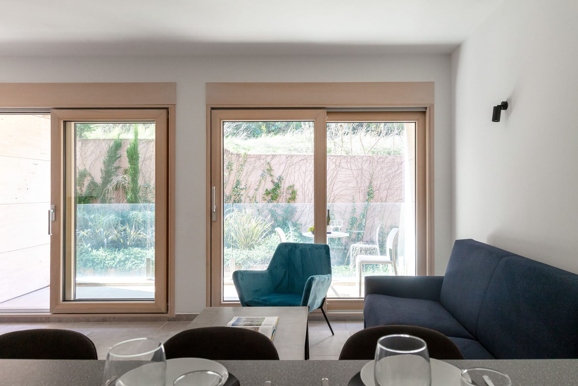 Living room in an apartment in Kotor, Montenegro: modern furniture, panoramic windows, and access to a terrace with a garden.