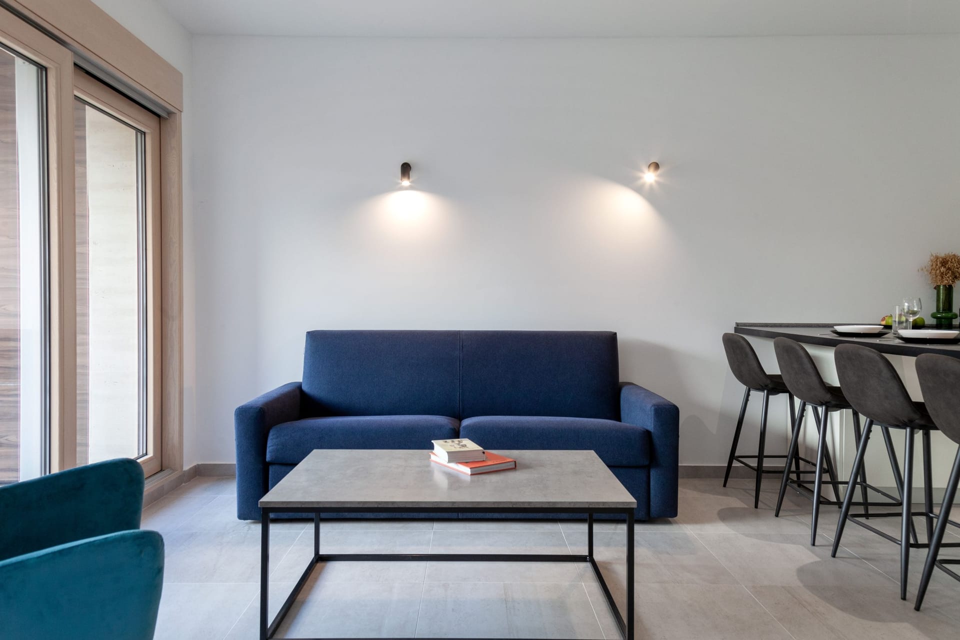 Modern living room with a blue sofa and a breakfast bar in an apartment in Kotor, Montenegro. Interior with a panoramic window.