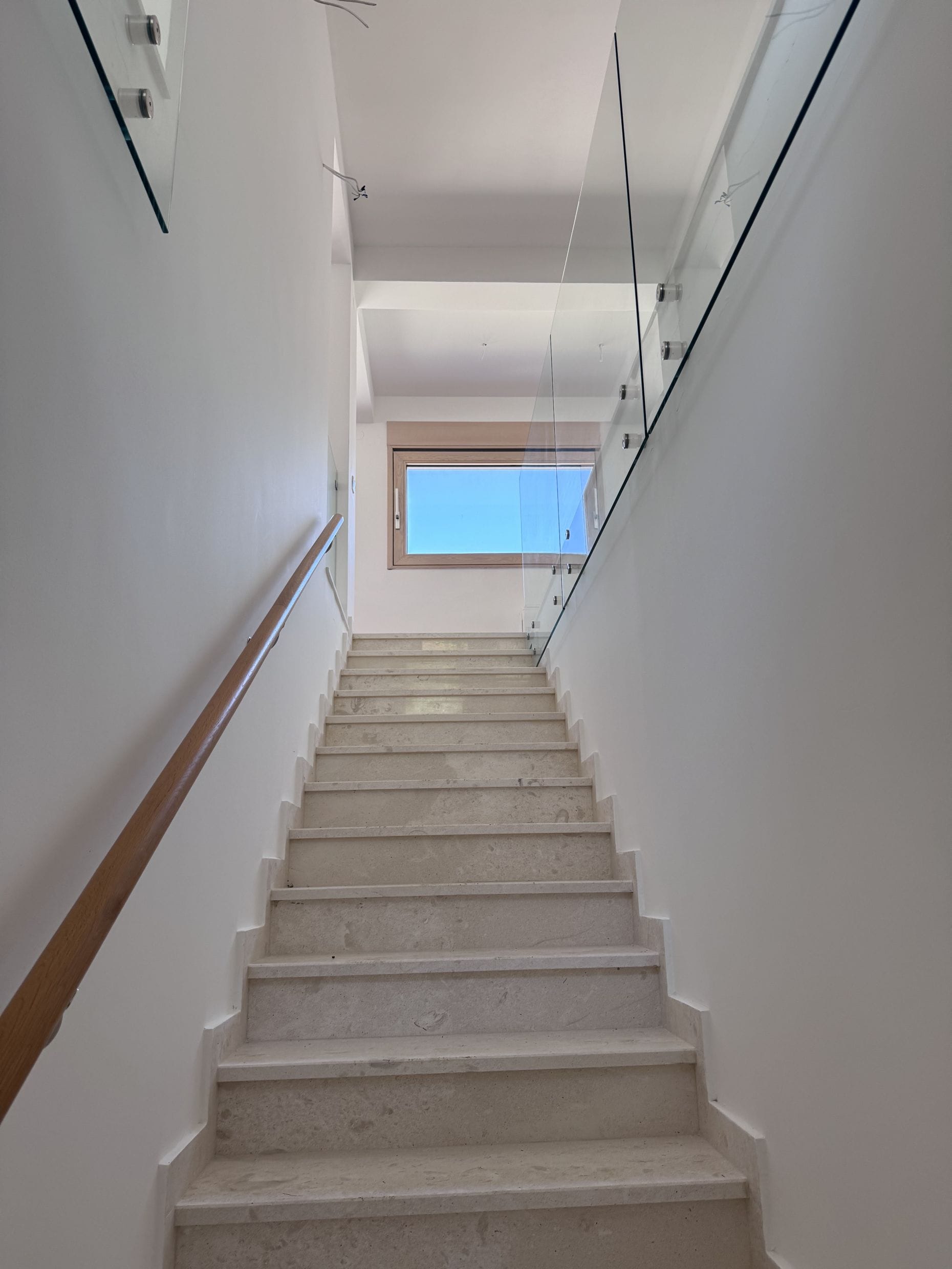 Staircase of light stone with glass railing in a modern apartment in Kotor, Montenegro.