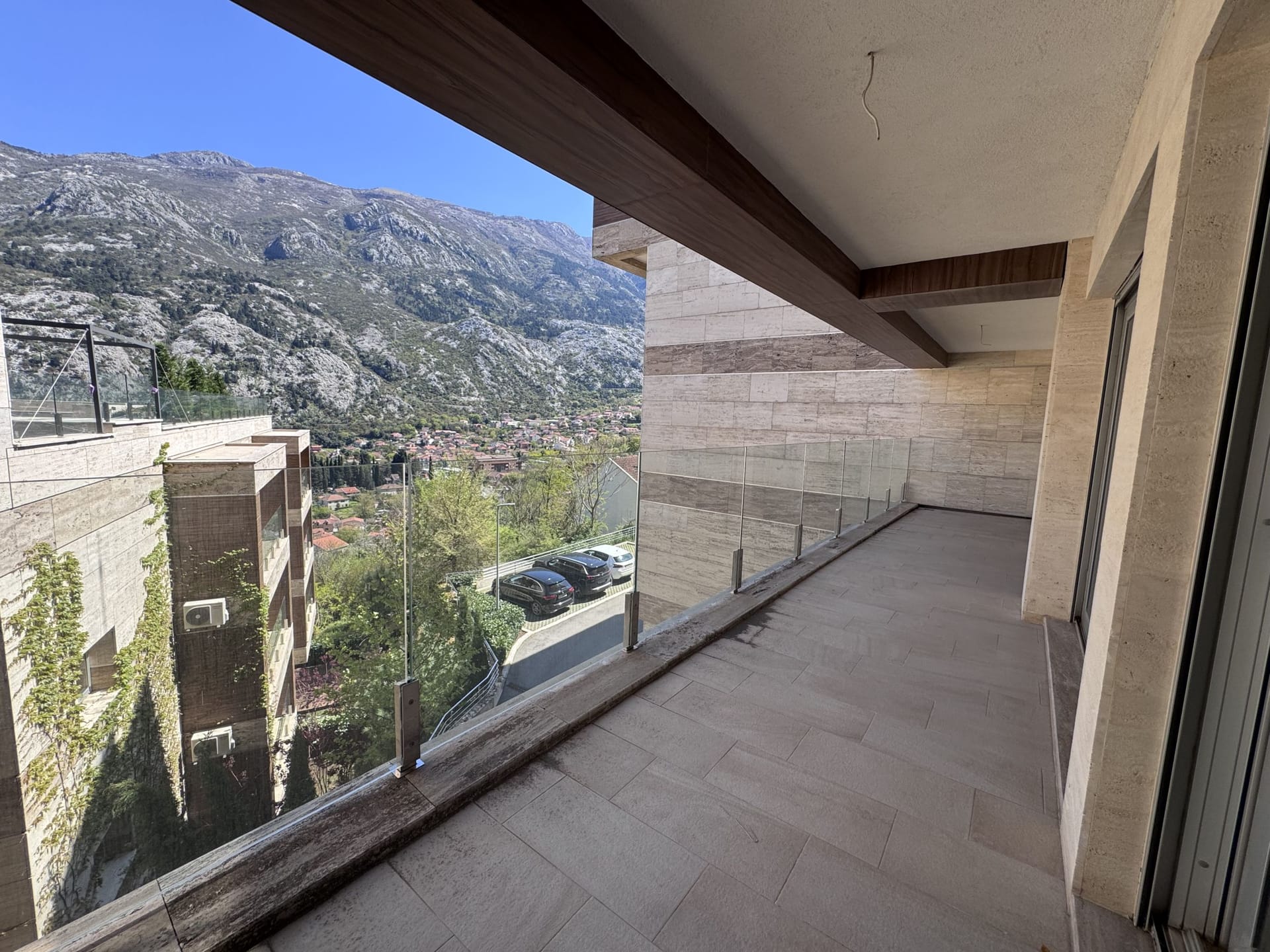Spacious balcony with stone finishes and panoramic mountain views in a modern apartment, Kotor, Montenegro.