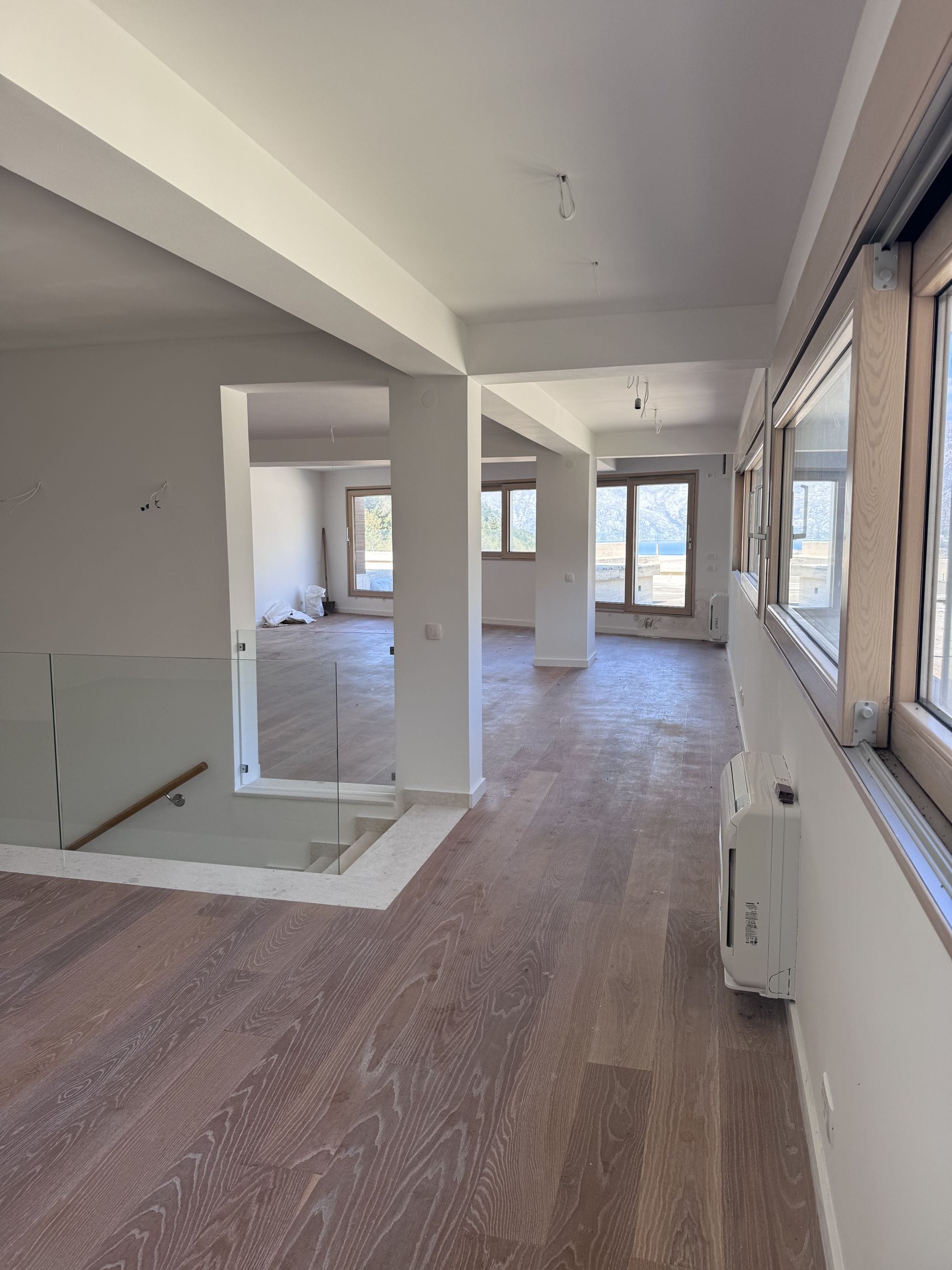 Spacious living room in a new building in Kotor, Montenegro: light finishes, wooden flooring, and sea views from the windows.