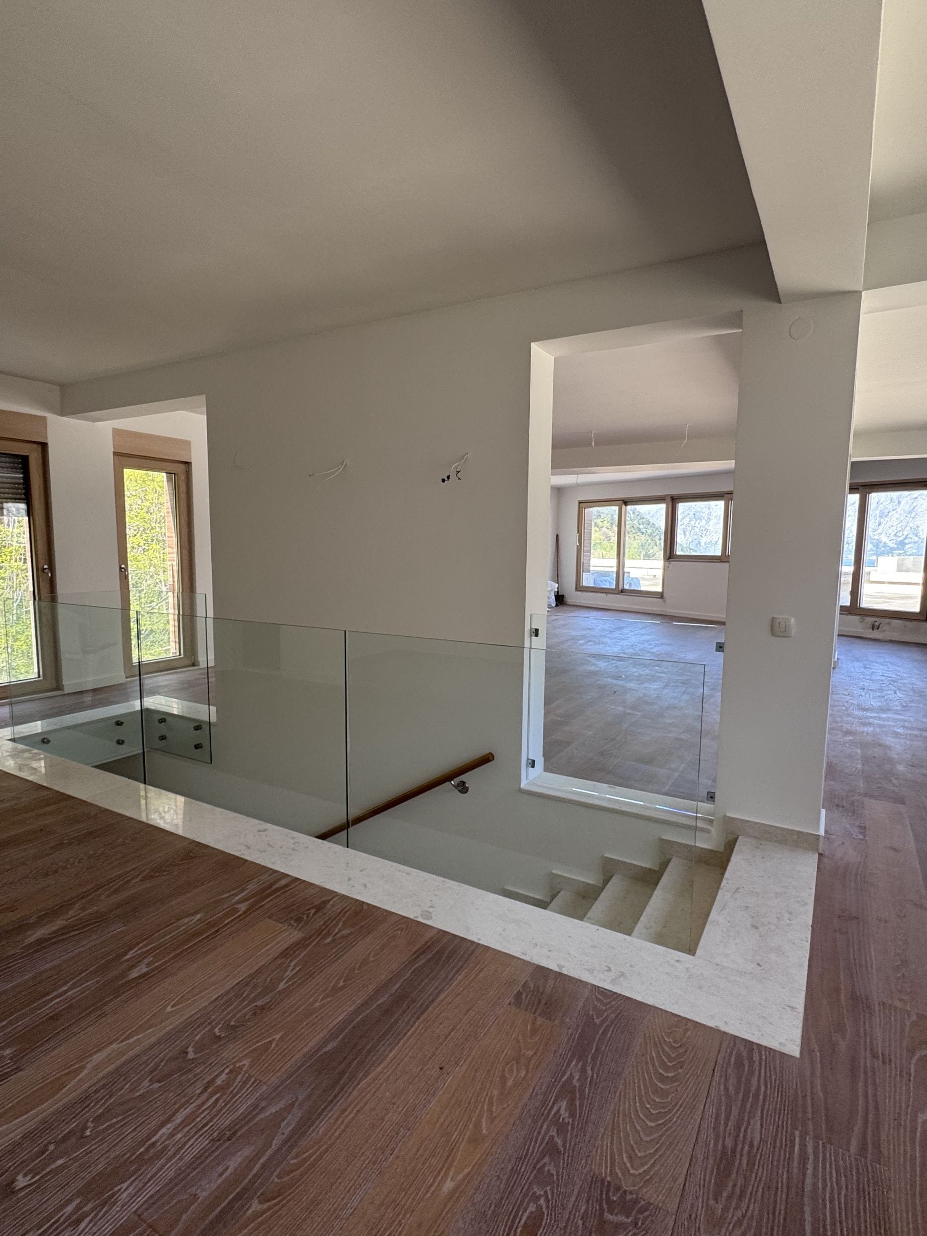 Living room interior with staircase and glass railing in a new apartment in Kotor, Montenegro. Bright finishes.