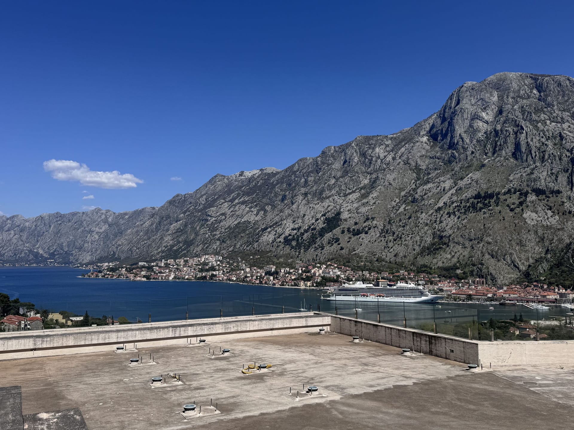 Panoramic view of Kotor Bay and the mountains from the terrace of a duplex in Kotor, Montenegro, with a cruise ship on the water.