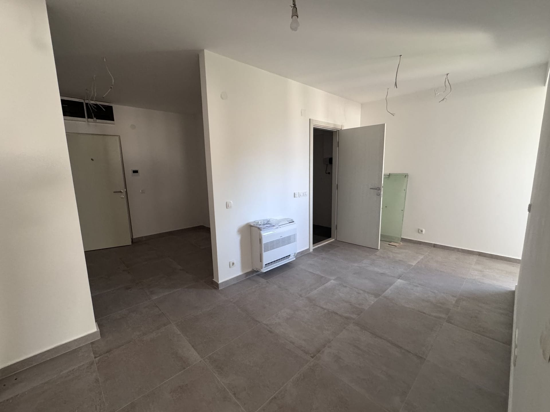 Living room in a new apartment in Kotor, Montenegro: light finishes, floor tiles, and installed air conditioner.