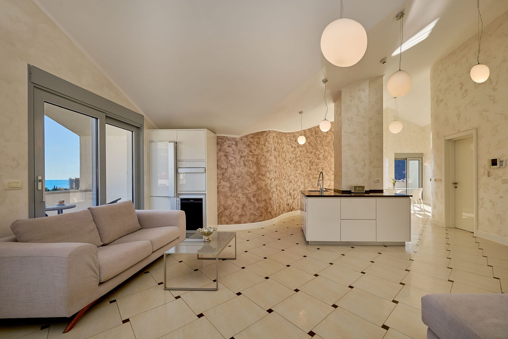 Modern living room with an island kitchen and sea view in an apartment, Budva, Montenegro. Bright interior, tile flooring.
