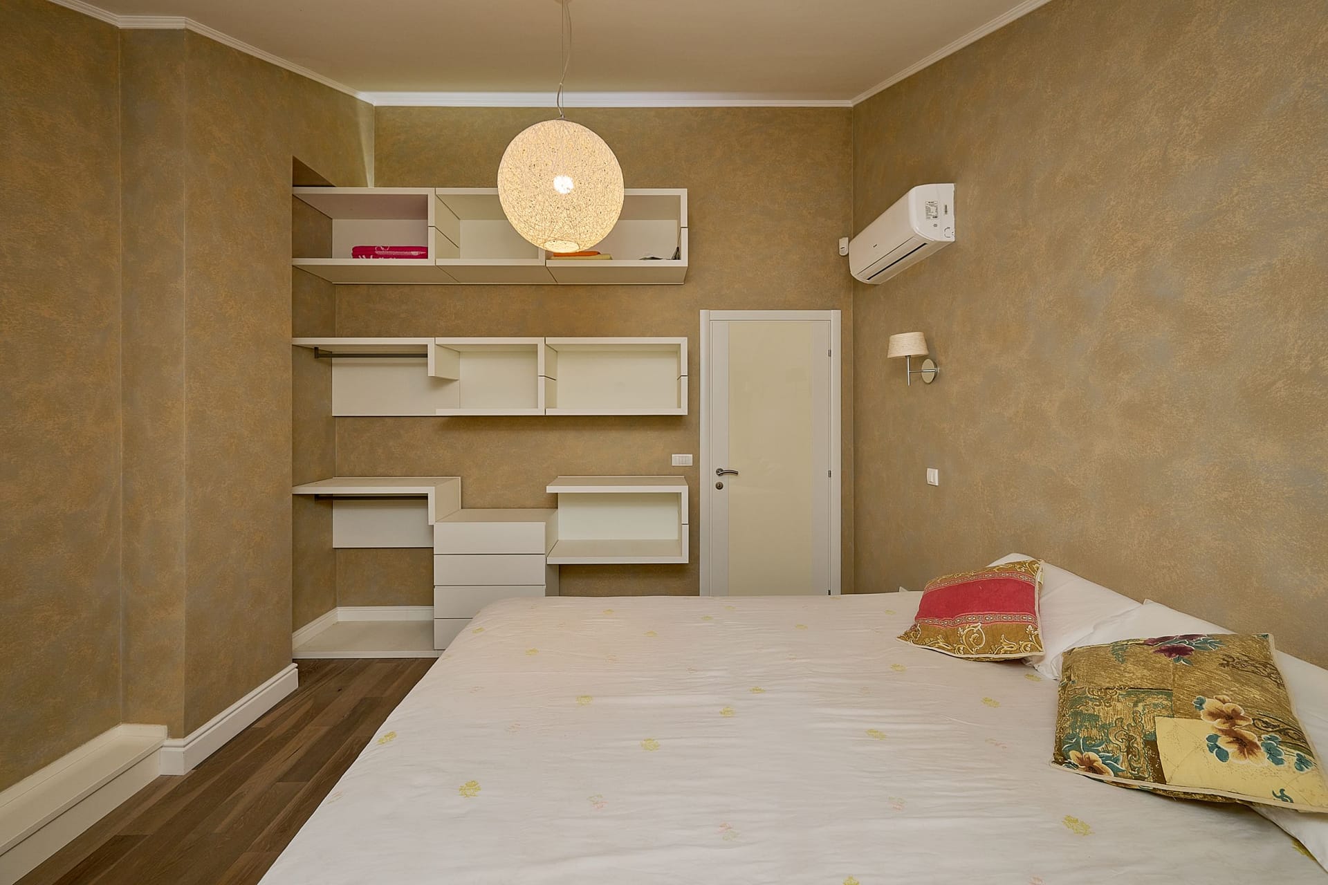 Bedroom in an apartment in Budva, Montenegro: double bed, open storage system, and air conditioner.