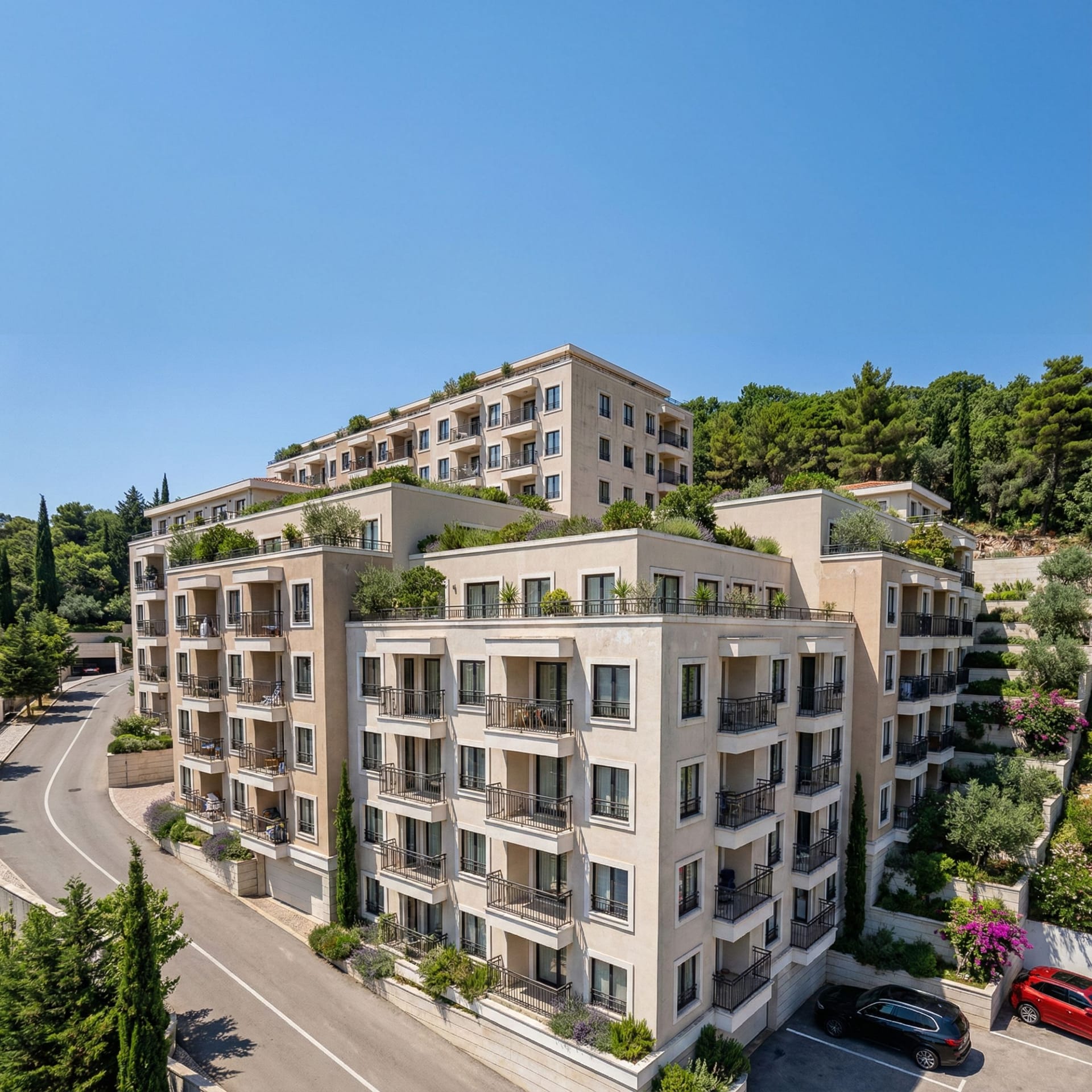 Modern residential complex with terraces and landscaping in Budva, Montenegro: view of the building facade and adjacent road.