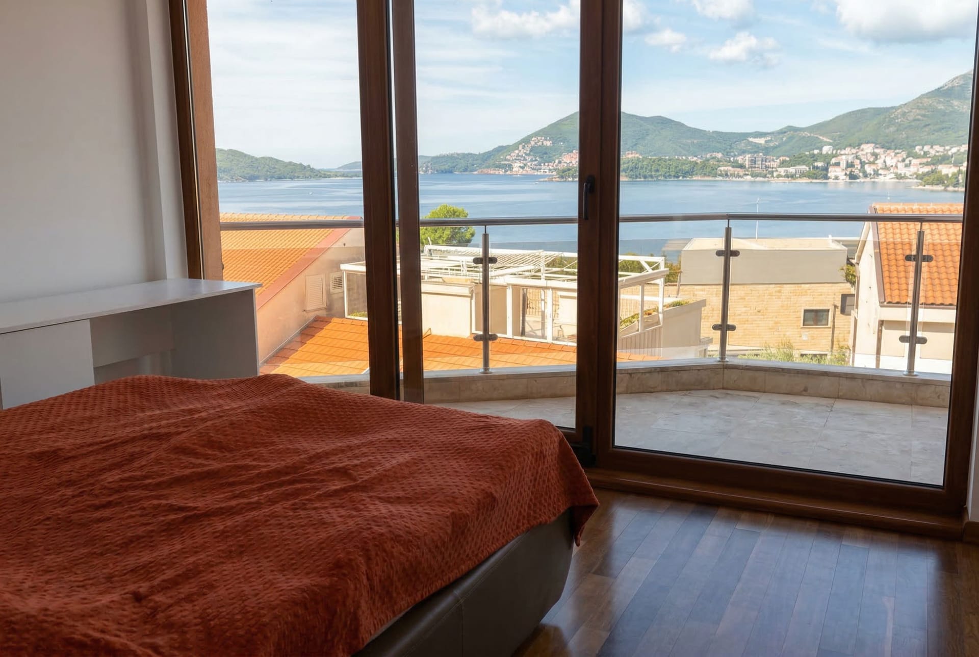 Penthouse bedroom in Kamenovo, Montenegro: panoramic sea view, terrace, double bed, and parquet flooring.