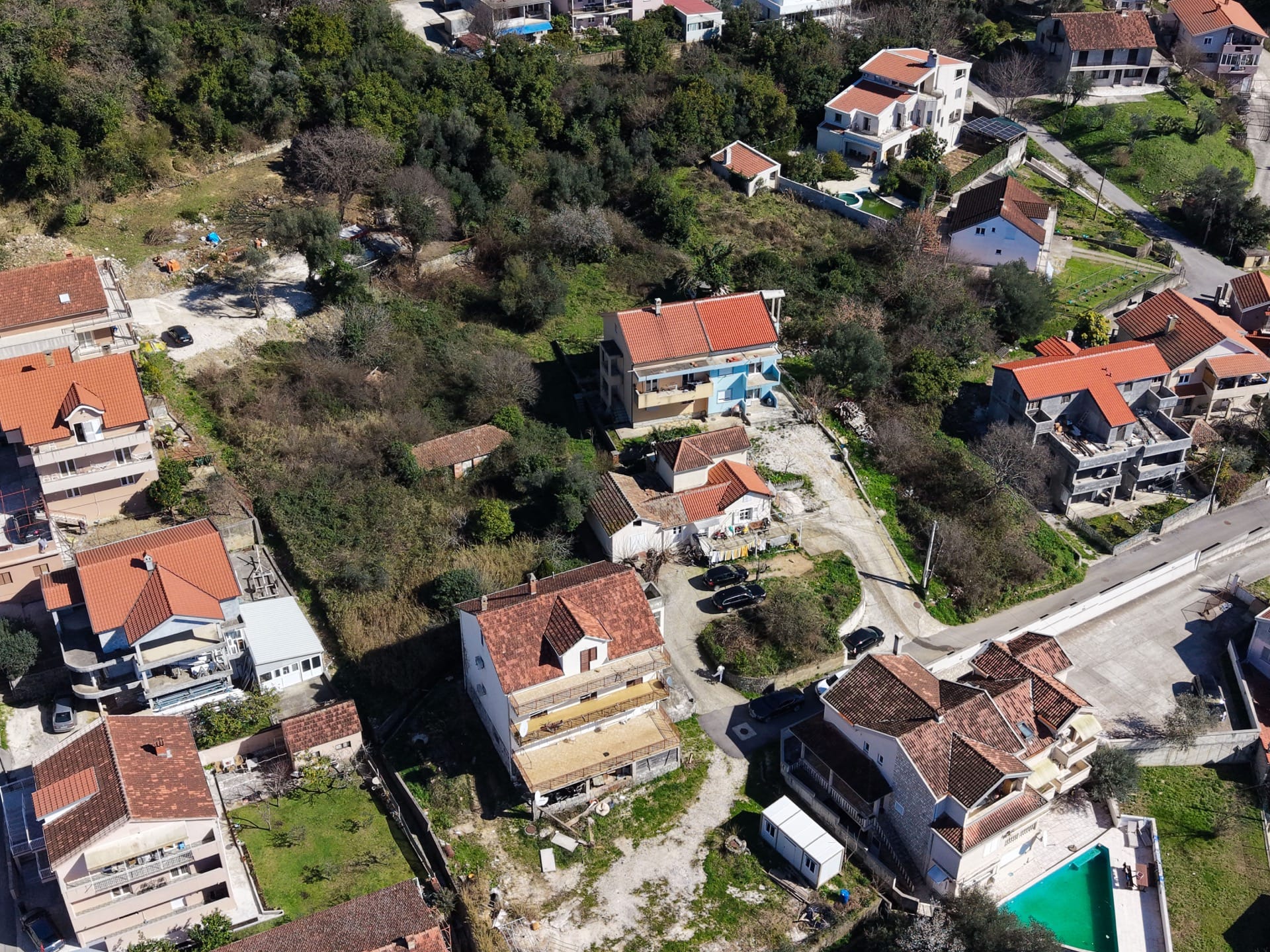 Aerial view of a plot of land and residential houses with tiled roofs in Tivat, Montenegro.