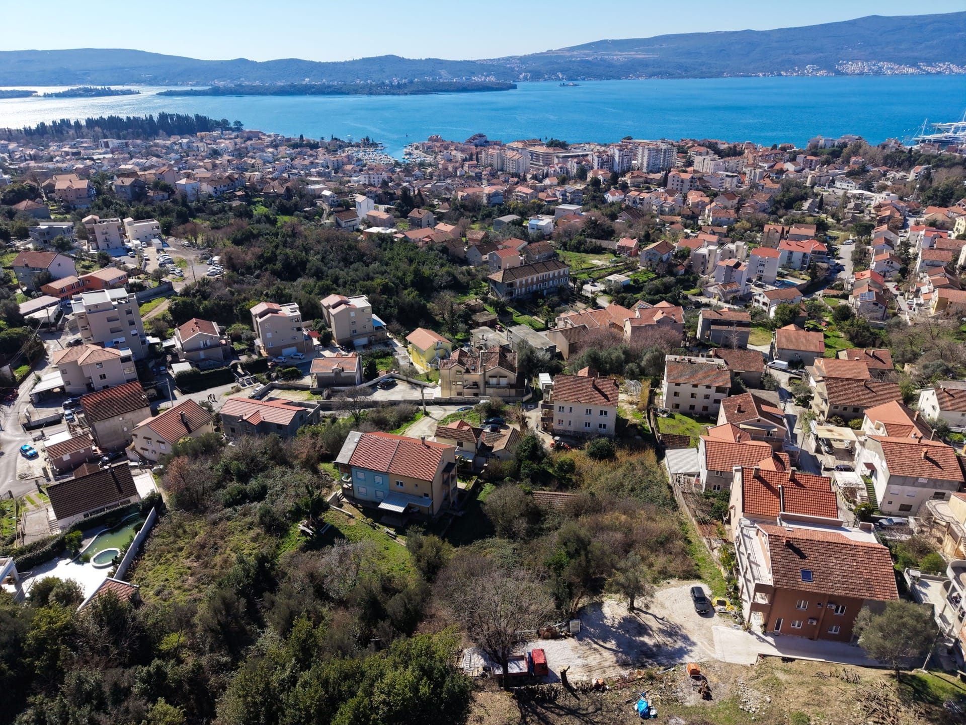 Aerial view of a land plot in Tivat, Montenegro, with panoramic views of the sea and city development.
