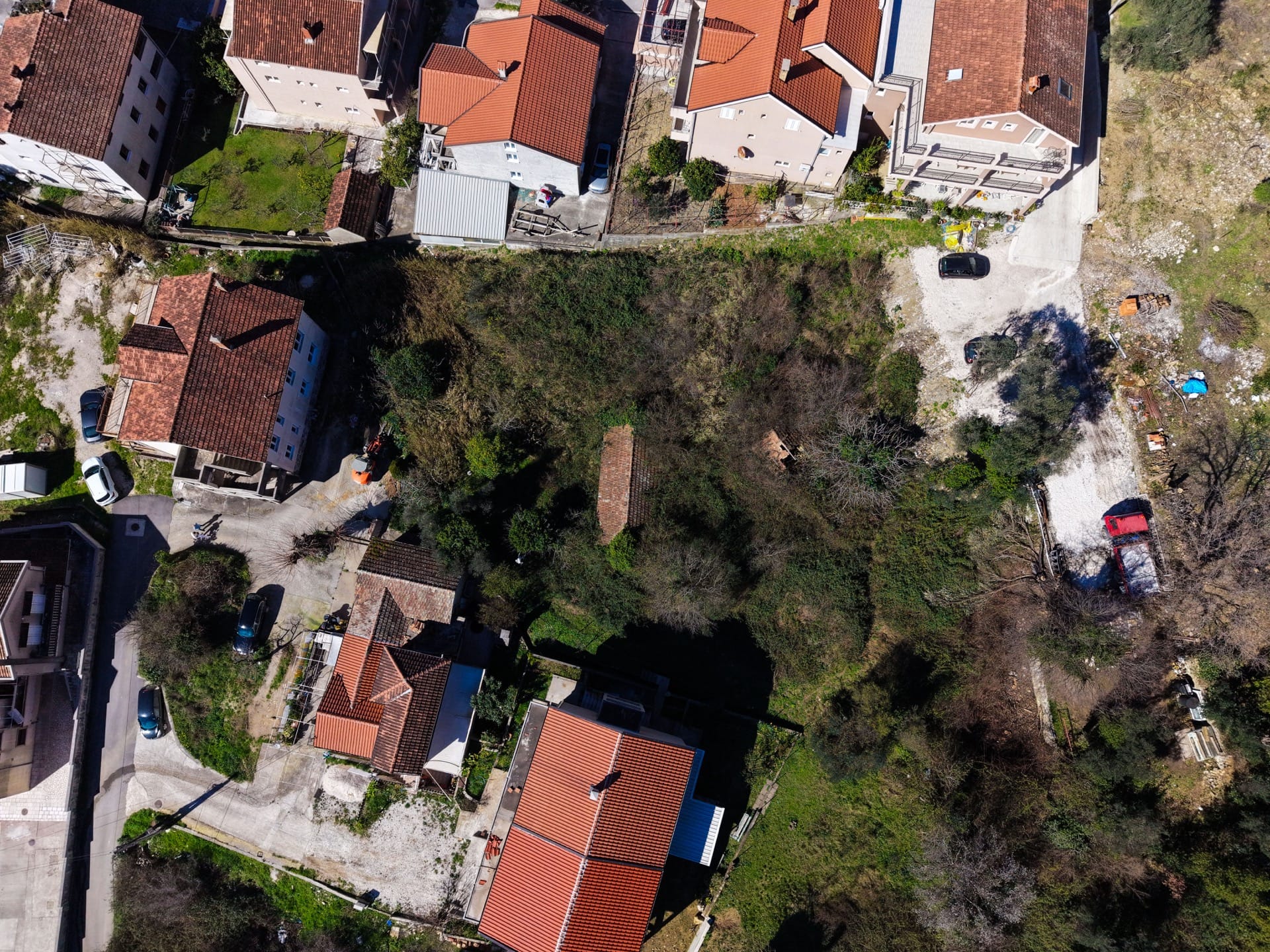 Aerial view of a building plot in Tivat, Montenegro, among residential houses with red roofs.