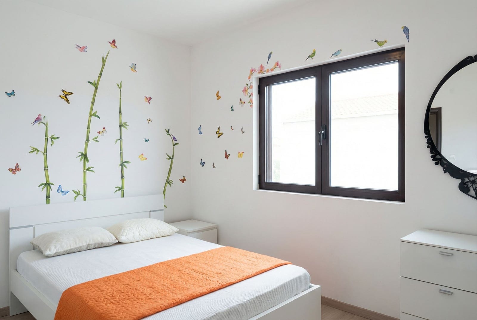 Bright bedroom in an apartment in Bečići, Montenegro: white furniture, wall decor with bamboo and butterflies, large window.