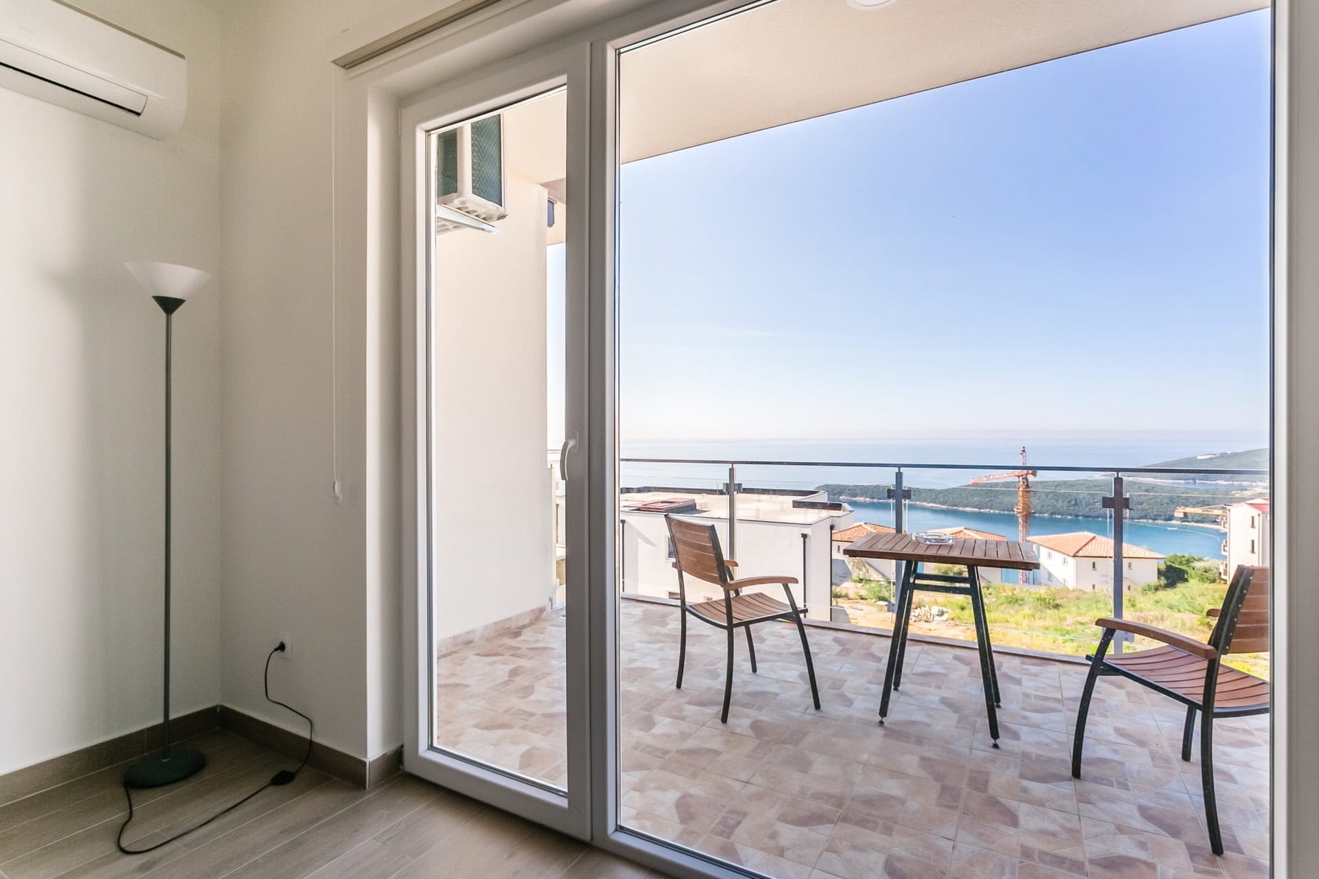 Balcony with furniture and panoramic sea view in the apartment, Seoce, Budva, Montenegro. Modern interior with access to the terrace.