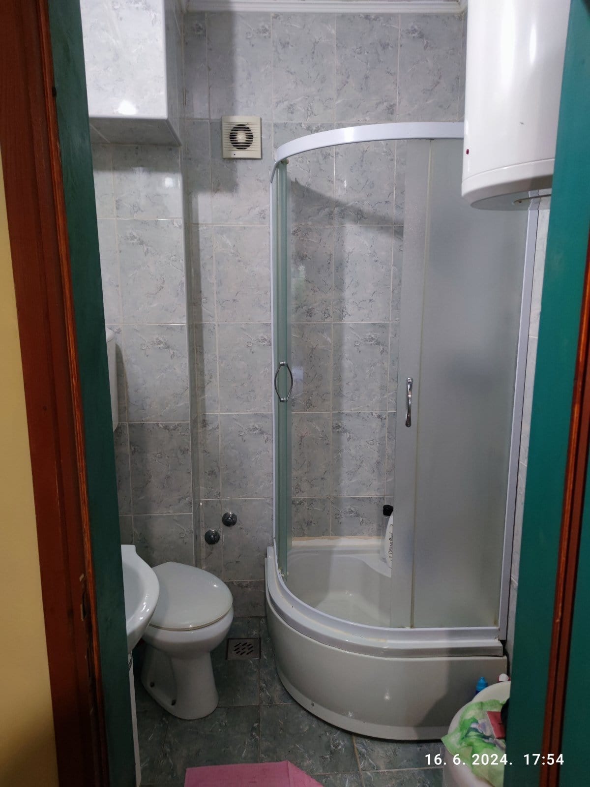 Bathroom in a house in Igalo, Montenegro: shower cabin, plumbing fixtures, and light-colored tiles on the walls and floor.