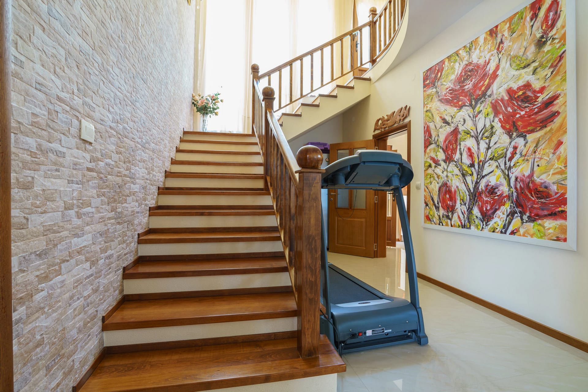 Interior of a house in Sutomore, Montenegro: wooden staircase, stone finishes, and a treadmill in the hall.