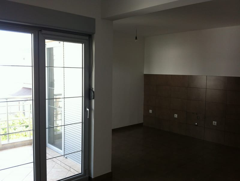 Kitchen interior in an apartment in Petrovac, Montenegro: dark tile, access to a balcony with panoramic glazing.
