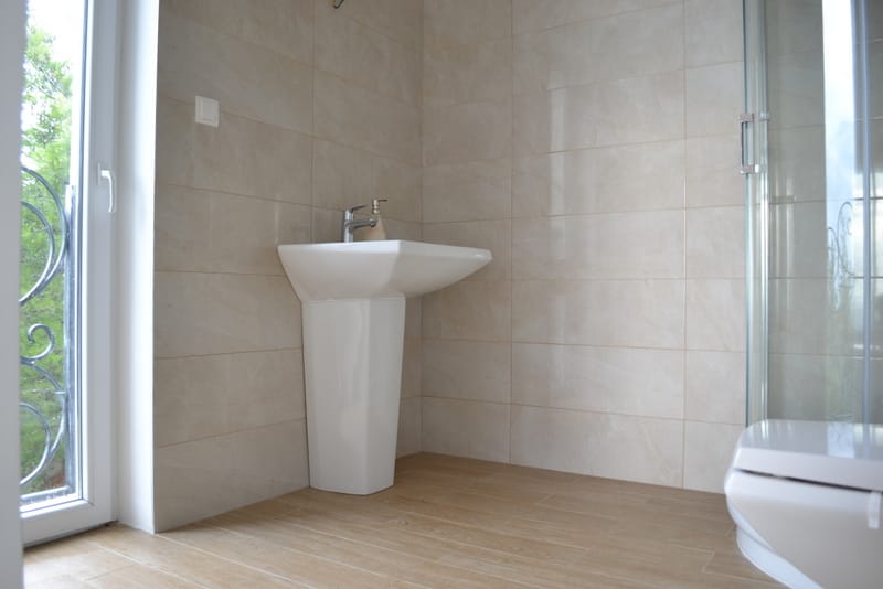 Bathroom with a shower cabin in a house in Shushan, Montenegro: light tiles, a sink, and access to the balcony.