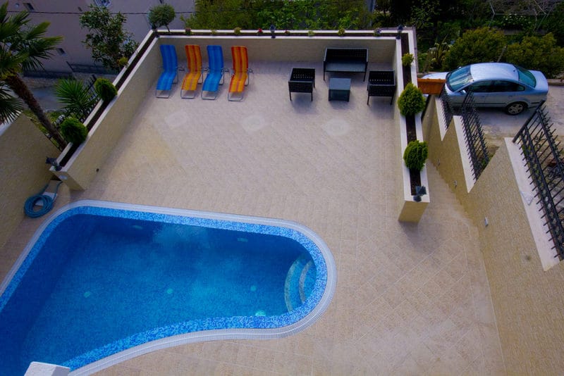 Outdoor pool and terrace with sun loungers by the house in Dobri Vody, Montenegro: top view of the relaxation area.