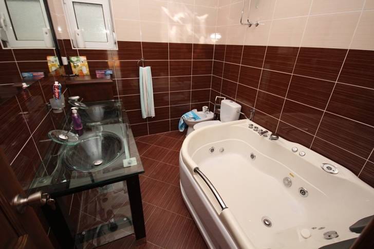 Bathroom with a jacuzzi and glass sink in a house, Dobri Vody, Montenegro. Modern brown tile finish.