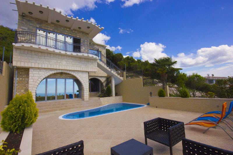 Two-story villa with a pool and terrace in Dobra Voda, Montenegro: stone finishes, panoramic windows, and sea views.