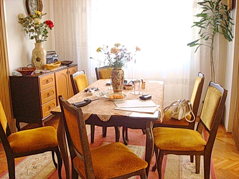 Cozy living room with dining area in a house, Baošići, Montenegro: wooden table, chairs with yellow upholstery, and parquet flooring.