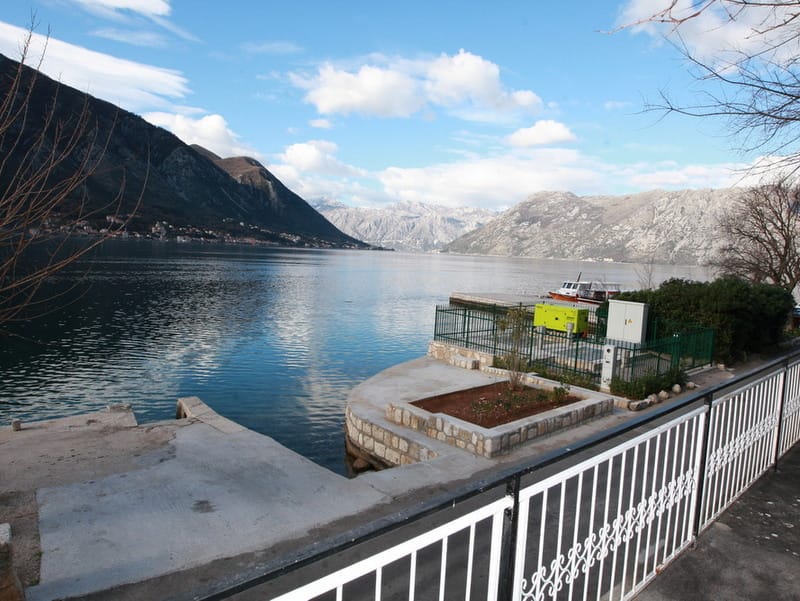 View of the Bay of Kotor and a private pier by the house in Dobrota, Montenegro: waterfront, mountains, and sea view.