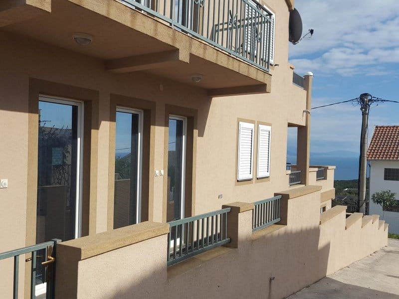 House facade in Krimovica, Montenegro: beige finish, balconies with metal railings, and a panoramic sea view.