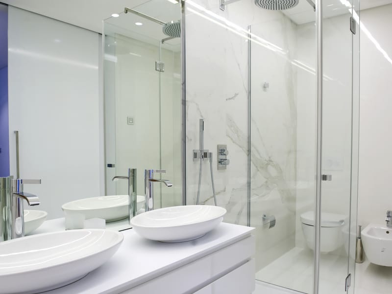 Modern bathroom with marble-look finishes in Dukley apartments, Bečići, Montenegro: two sinks and a shower.
