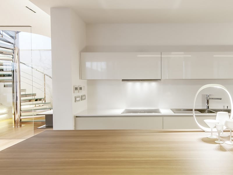 Modern kitchen in a Dukley apartment, Bečići, Montenegro: white glossy cabinets, wooden countertop, and a spiral staircase.