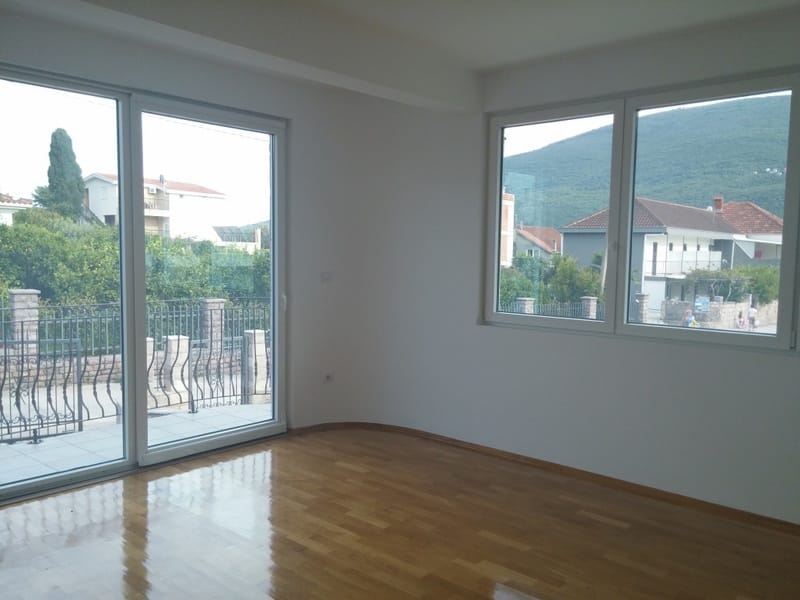 Bright living room with panoramic windows and mountain views in a house in Đenovići, Montenegro, parquet flooring and access to the terrace