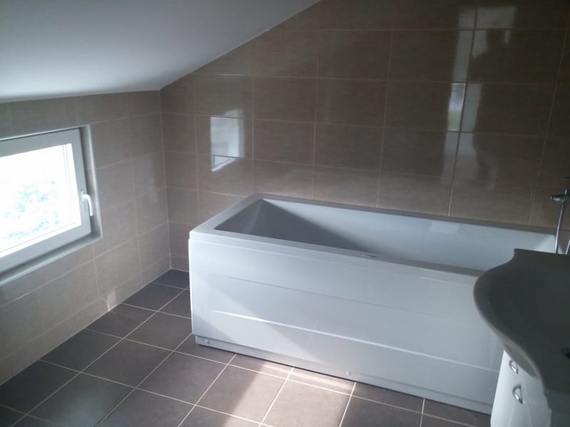 Bathroom with a white bathtub and beige tiles in a house in Đenovići, Montenegro. Skylight and modern design.