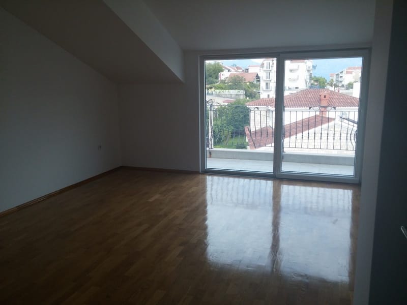 Bright living room with parquet flooring and access to the balcony in a house in Đenovići, Montenegro, with city and mountain views.