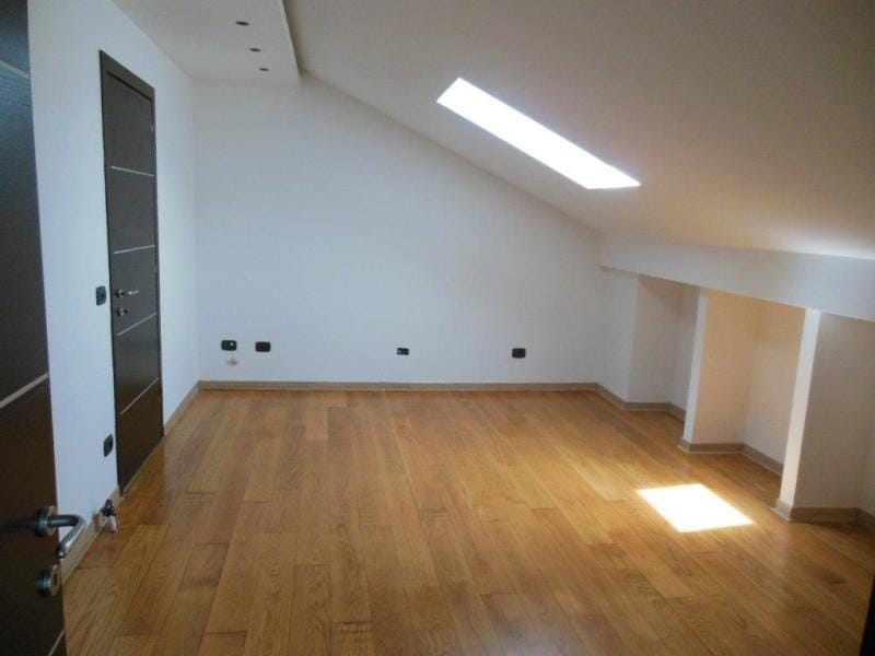 Bright attic bedroom with parquet flooring and a skylight in an apartment, Rafailovici, Montenegro.