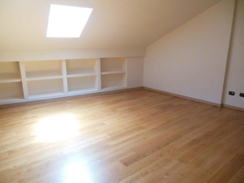 Bright attic bedroom in an apartment in Rafailovici, Montenegro: wooden floor, built-in shelves, and a skylight.