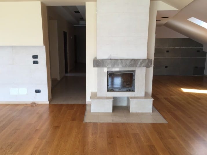 Living room with a fireplace and parquet floor in an apartment in Rafailovici, Montenegro: modern finishes and a sloped ceiling.