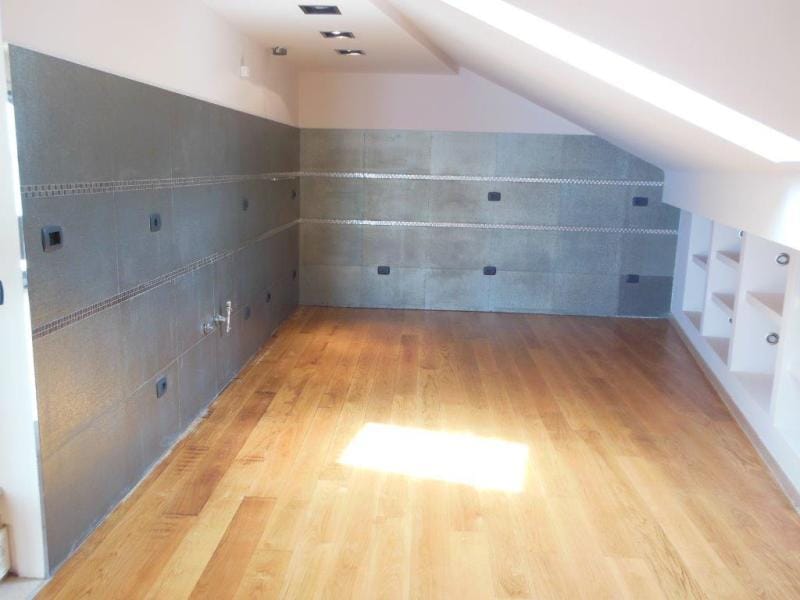 Modern kitchen in the apartment attic in Rafailovici, Montenegro: gray tile, wooden floor, and built-in shelves.