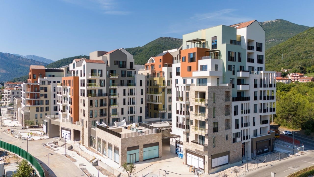 Modern residential complex in Porto Montenegro, Tivat, Montenegro: view of multi-story buildings with terraces and mountains.