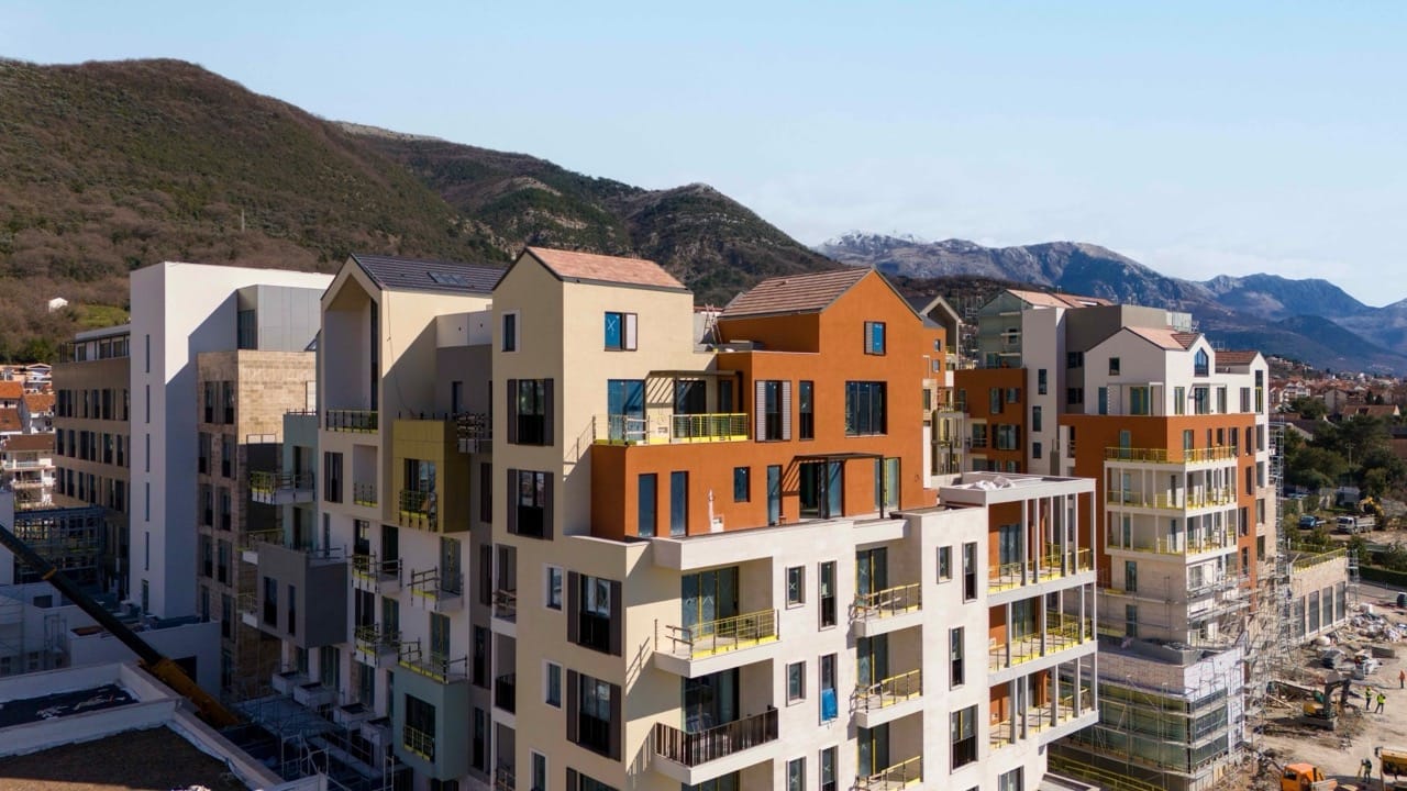 Residential complex under construction in Porto Montenegro, Tivat, Montenegro: modern building facades against a mountain backdrop.