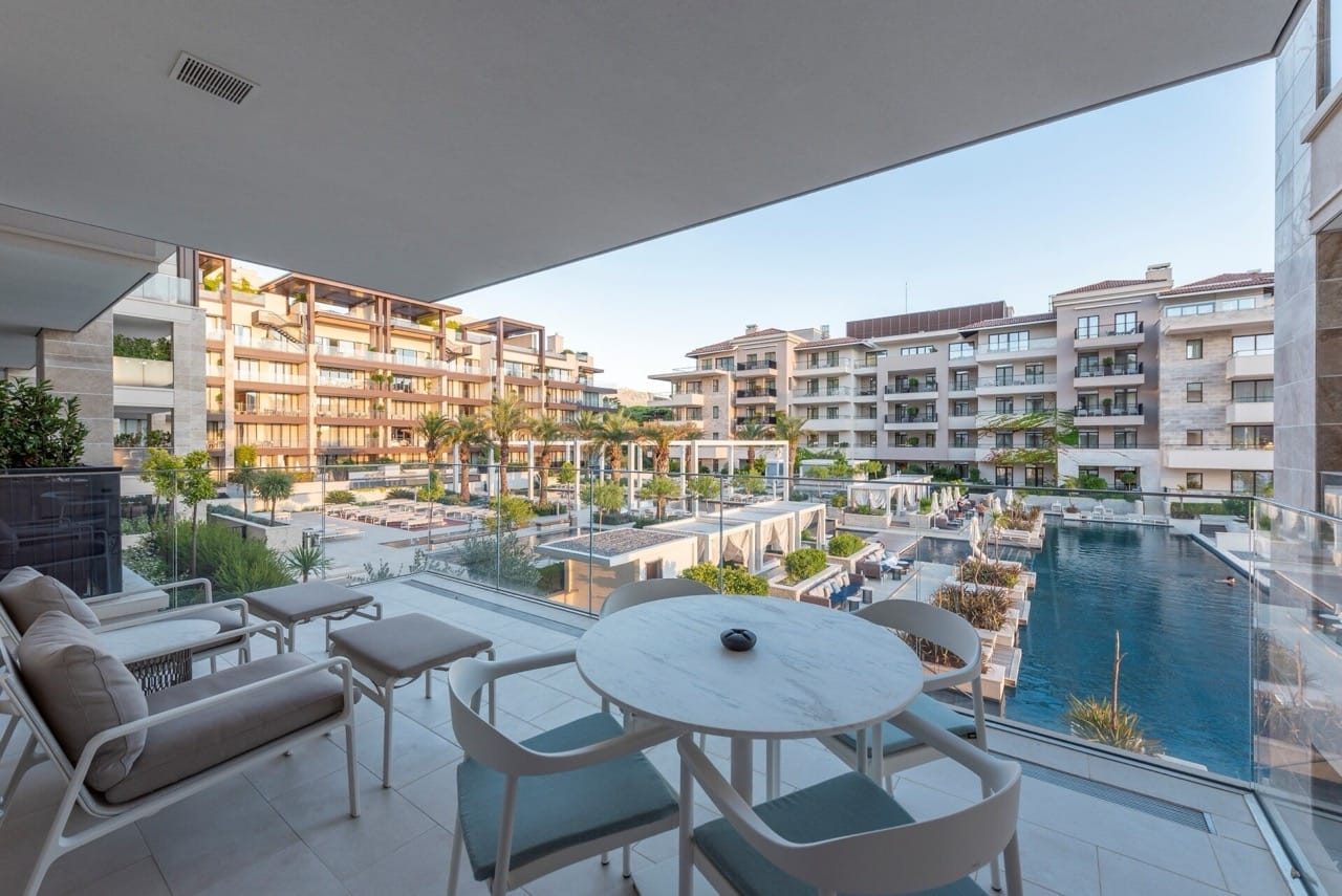 Apartment terrace in Porto Montenegro, Tivat, Montenegro with a view of the pool, modern furniture, and landscaping.