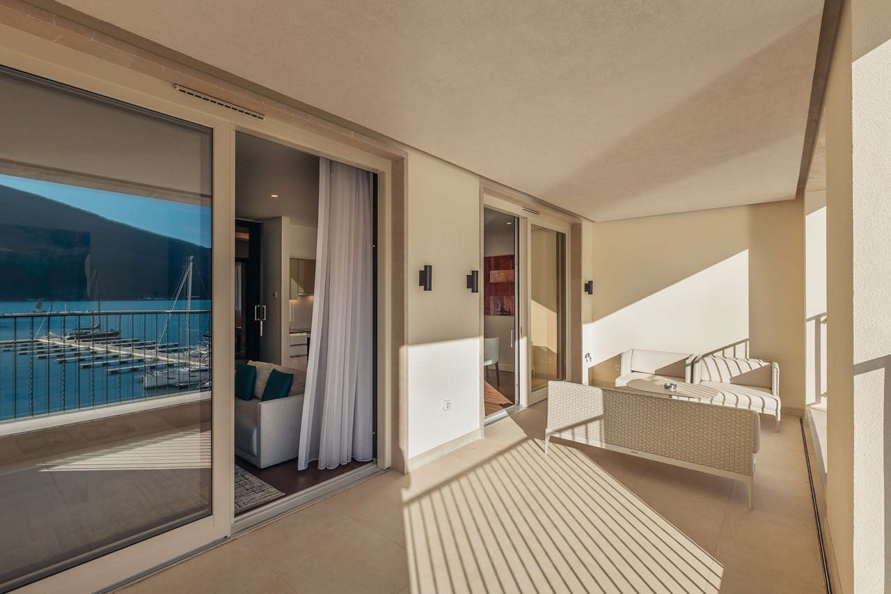 Spacious terrace with wicker furniture in an apartment in Portonovi, Kumbor, Montenegro, overlooking the yacht marina and the sea.