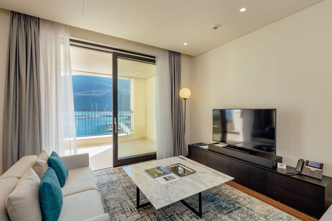 Living room in an apartment in Portonovi, Kumbor, Montenegro: modern furniture, a marble table, and a view of the marina with yachts.