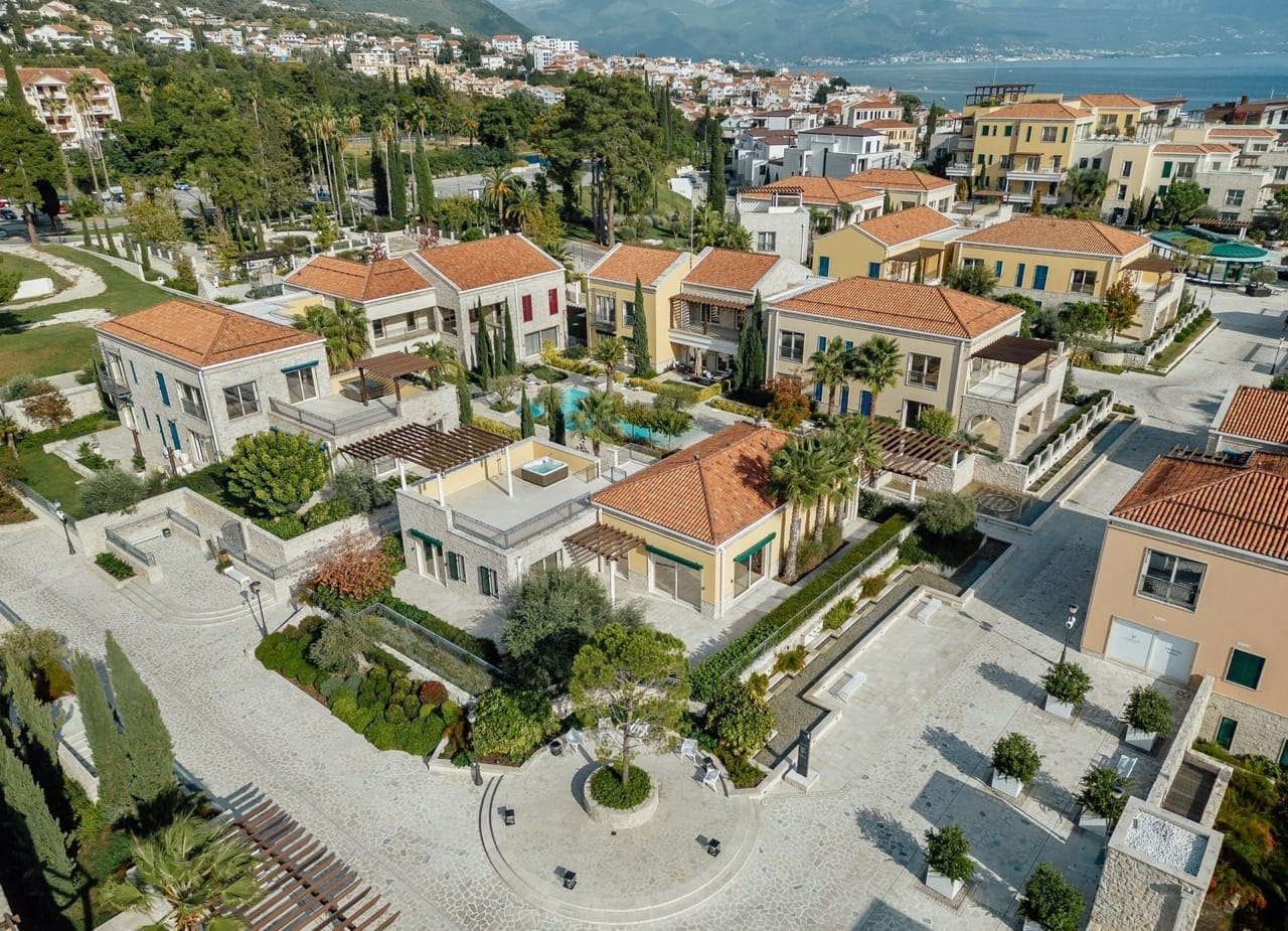 Aerial view of the luxury Portonovi residential complex in Kumbor, Montenegro: villas with tiled roofs and a swimming pool.