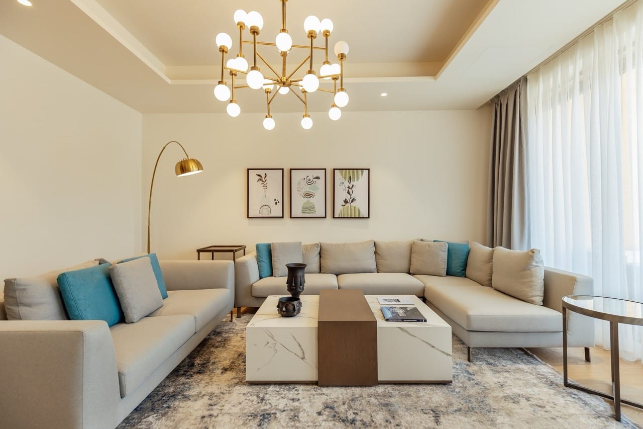 Modern living room in an apartment in Portonovi, Kumbor, Montenegro: light-colored sofas, a marble table, and a designer chandelier.
